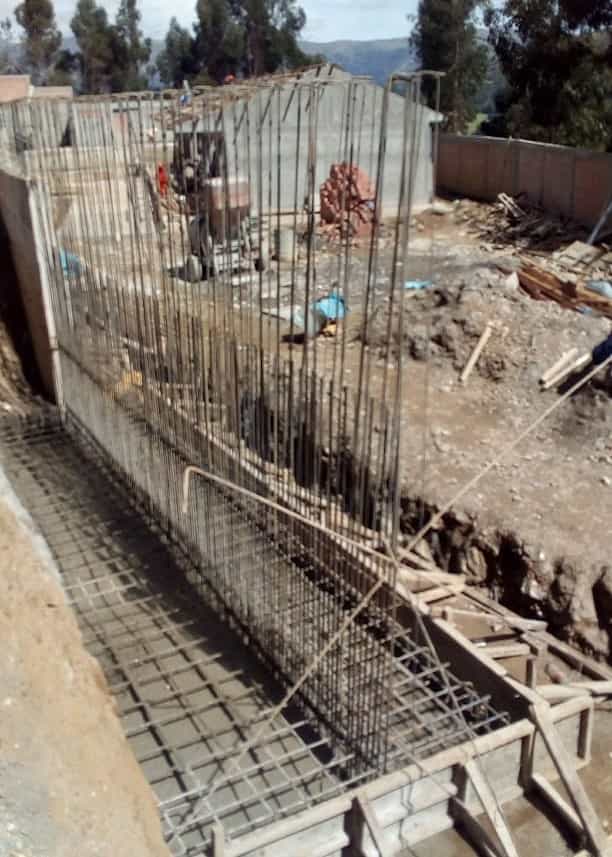 Encofrado de madera y apuntalamiento temporal para un muro de contención o cimentación en la construcción de un centro educativo en Huánuco.